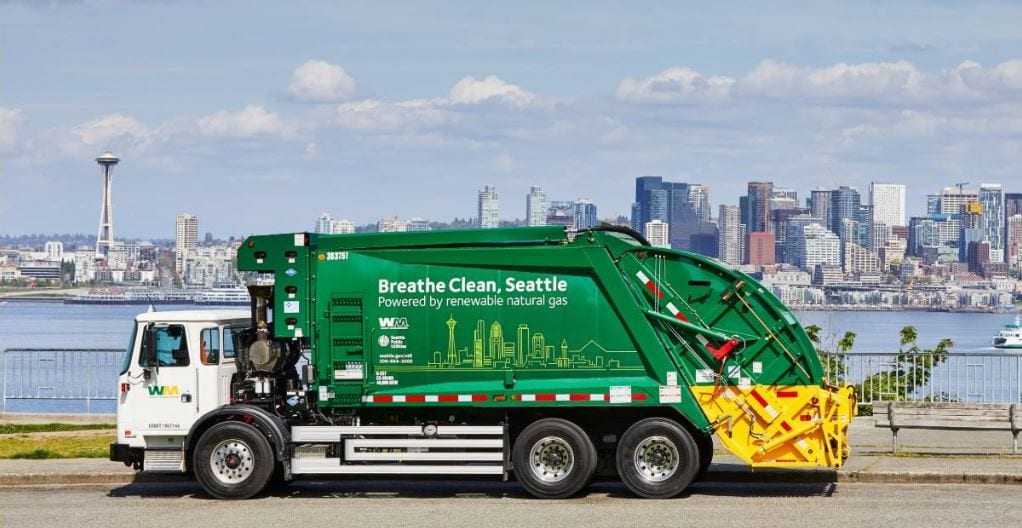 Photo of a collection truck powered with green energy, with the Seattle downtown skyline in background