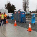 Image of Honey Bucket portable toilets and hygiene station with city workers.