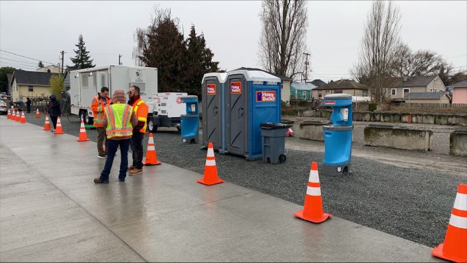 Image of Honey Bucket portable toilets and hygiene station with city workers.