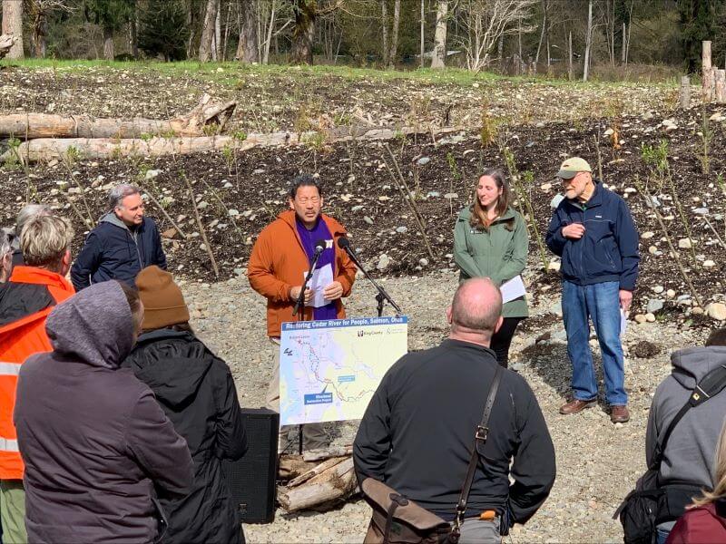 Photo of Mayor Bruce Harrell speaking at the press event flanked by King County Executive Dow Constantine, and other officials at the Riverbend Project site.