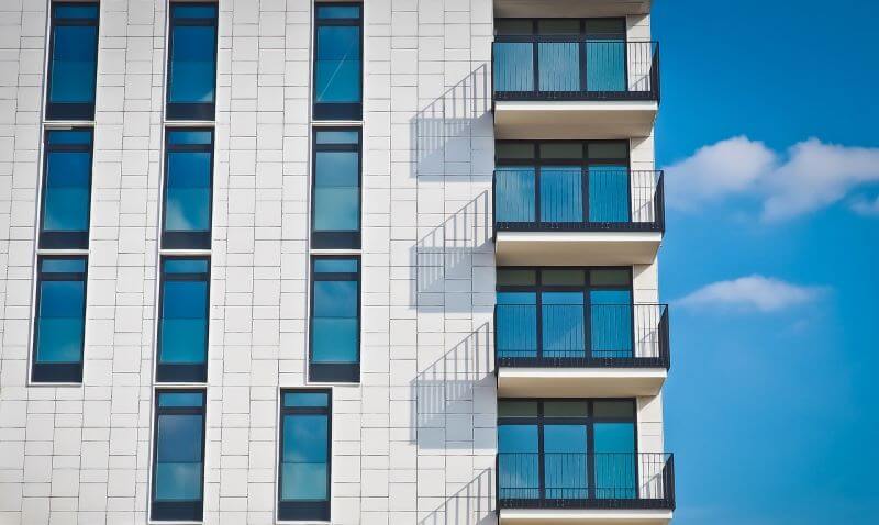 Stock photo of a contemporary apartment building facade with blue sky in background.