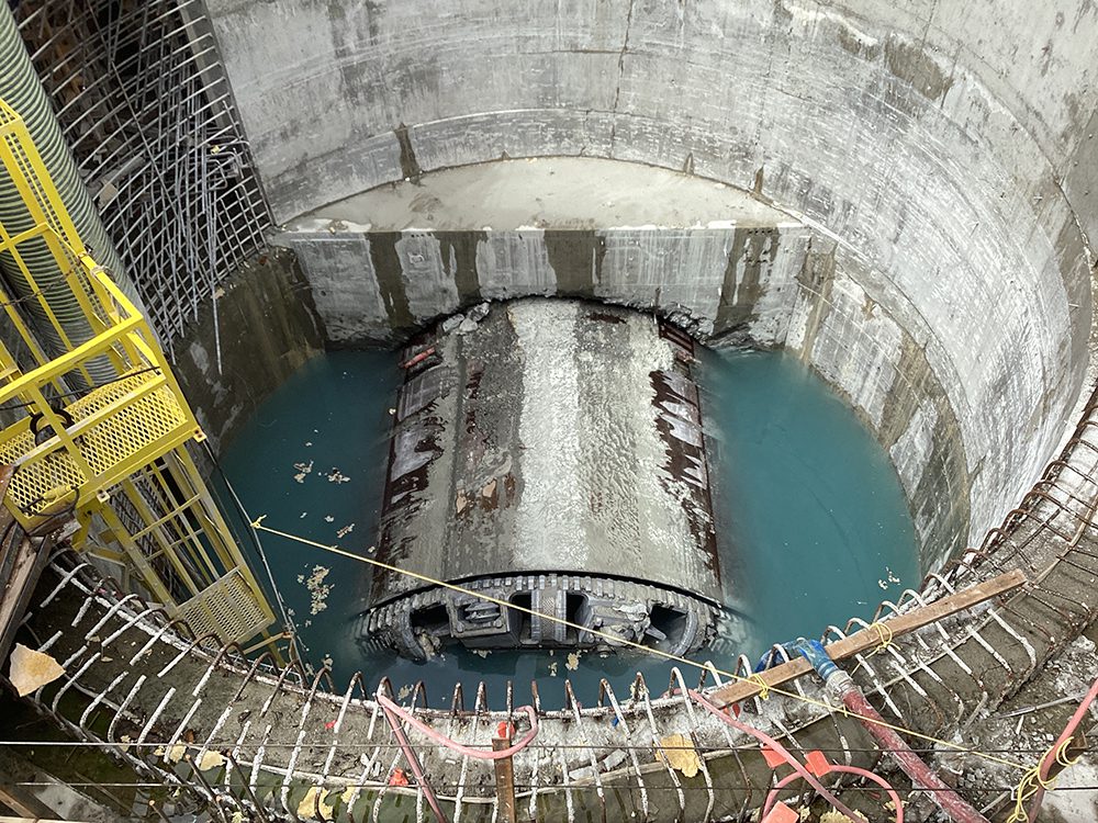 The Mudhoney tunnel-boring machine sits half-submerged in water at the bottom of a large round concrete shaft.