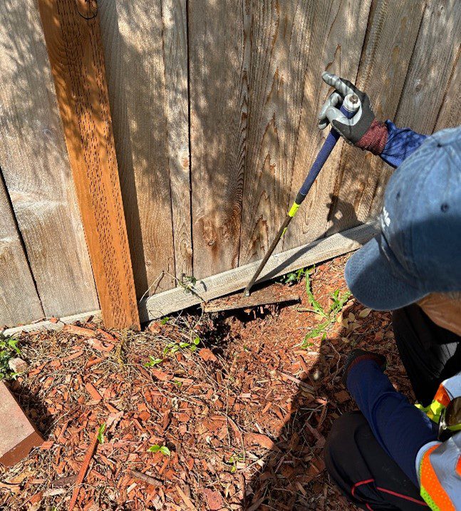 Using the bent cane tool by a fence to access a meter cover.