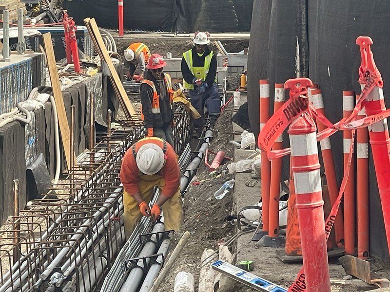 Construction workers on the Ship Canal Water Quality Project laying out pipes among concrete forms.