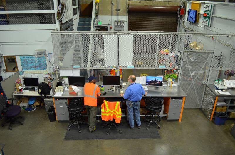 Overhead view of control center warehouse desk with two workers talking.