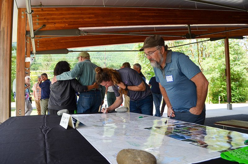 SPU employee looking at a commemorative map of the watershed on a table, while another signs the map.