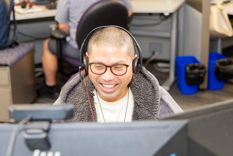 Smiling Customer Care agent talking to a customer on the phone.